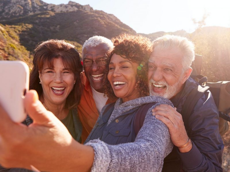 Group Of Senior Friends Posing For Selfie As They Hike Along Trail In Countryside Together